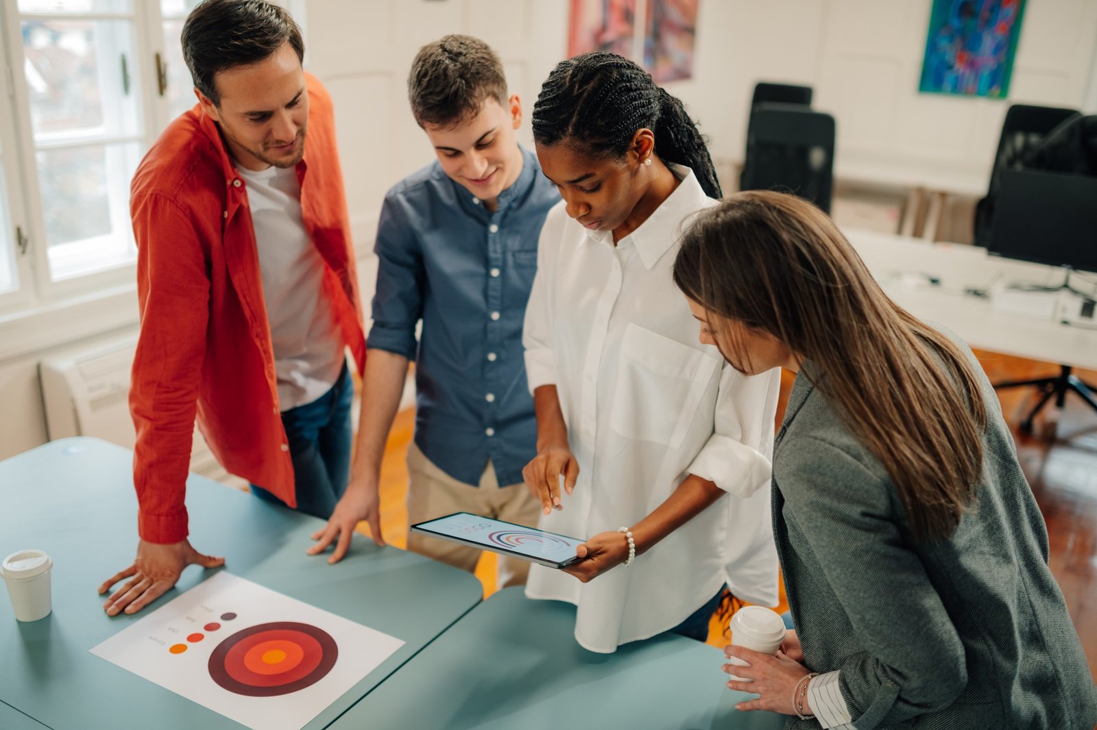 Marketing team analyzing data on digital tablet and printed charts during a meeting